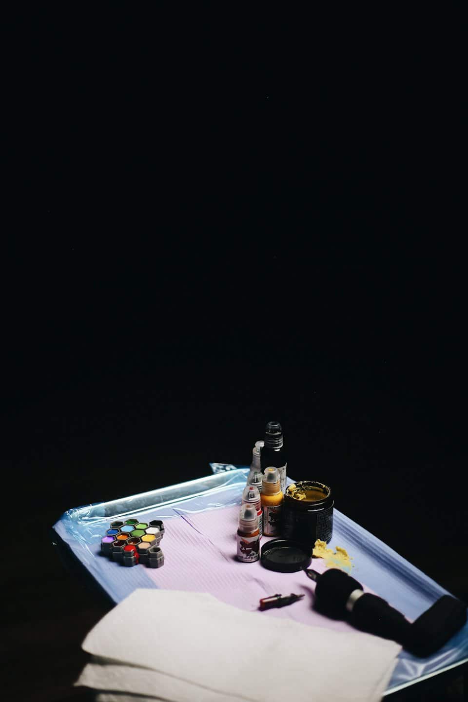 Tattoo equipment arranged on a mat with ink and a tattoo machine.